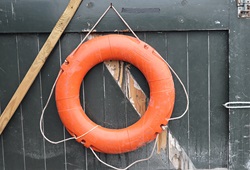 Orange life buoy hanging on wooden gate