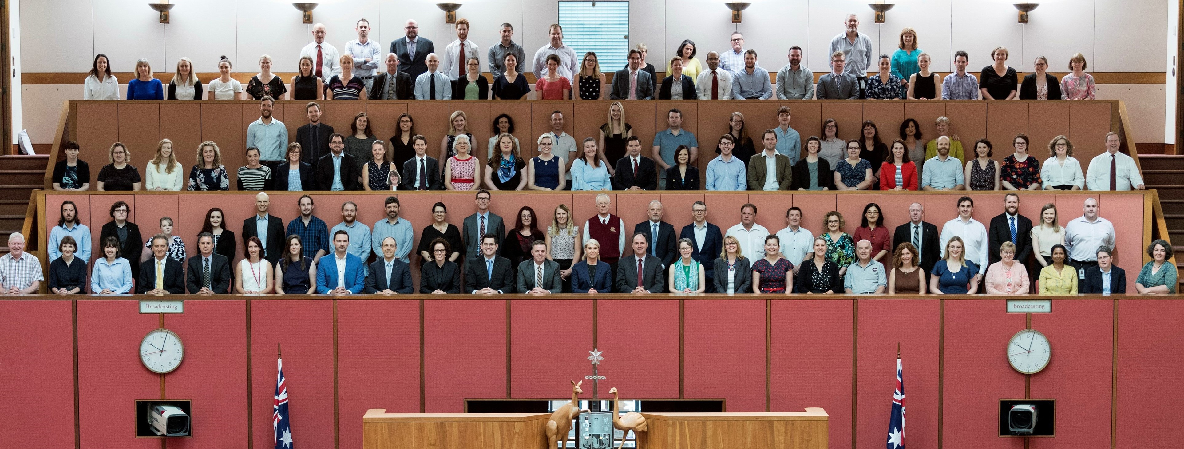 All members of the Department of the Senate sitting and standing on the mezzanine level of the Senate chamber behind and above the President's chair