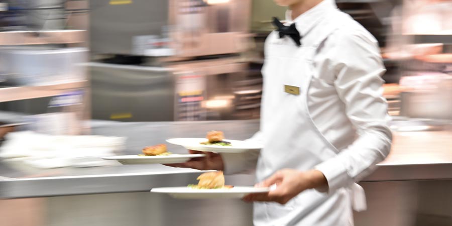 APH Catering and Events staff member carrying plates 