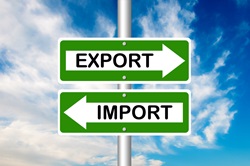 Sign reading import and export with arrows facing opposite directions against blue sky background