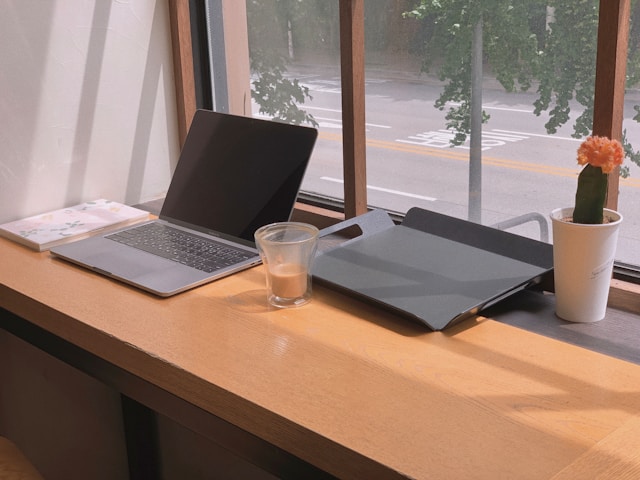 A half-drunk coffee on a desk with a turned off laptop and an empty work tray