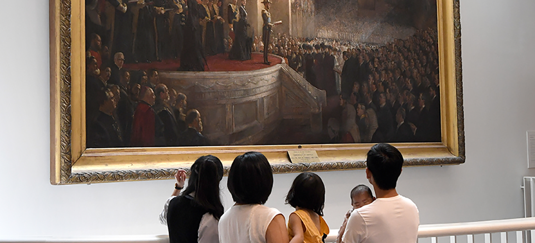 A guide discusses a painting by Tom Roberts 'Opening of the First Parliament of the Commonwealth of Australia by H.R.H The Duke of Cornwall and York (Later King George V), May 9, 1901'
