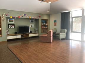 Figure 1.9 & 1.10 (from left to right): photo of indoor communal area; and view of outdoor communal area, including fire pit where family members can come and visit residents and participate in ceremonial activities.